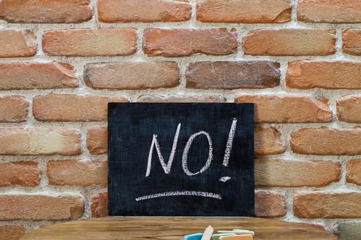 Chalk board with the word NO drown by hand and chalks on wooden table on brick wall background. photo