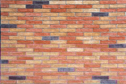 Brick wall with bricks in various colors, primarily in shades of red, orange, and beige, with some darker, almost black bricks. photo