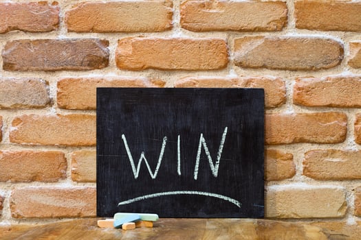 Chalk board with the word WIN drown by hand and chalks on wooden table on brick wall background. photo