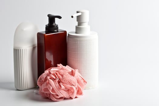 Bath cosmetic products and white sponge on light background. photo
