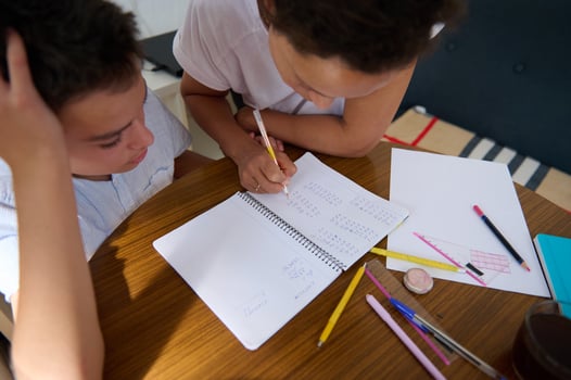 Mother helping son with homework at kitchen table photo