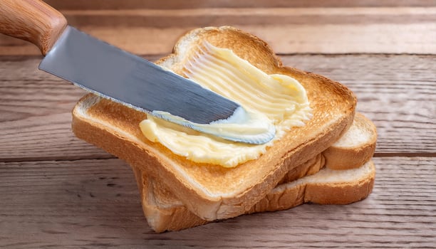 Knife spreading butter on toast bread on wooden background photo