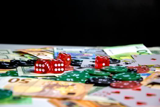 A close-up shot of a table with red dice, poker chips, and Euro banknotes scattered across the surface photo