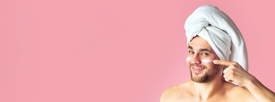 Male beauty care concept. Man uses face cream, panorama, free space photo