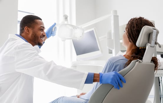 Cheerful african male dentist talking to woman patient sitting in dentist chair photo