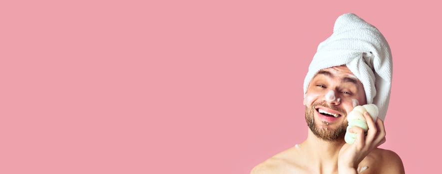 Funny millennial guy lathers his face with sponge, panorama photo