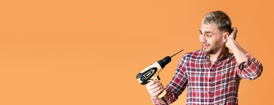 Funny man scratches his head and looks at drill photo