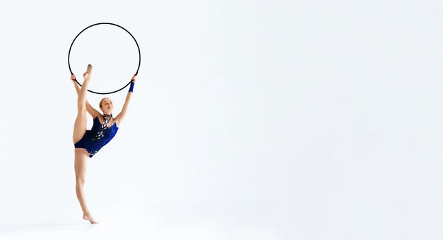 Professional athlete doing complicated gymnastic trick with hoop on white background, isolated photo