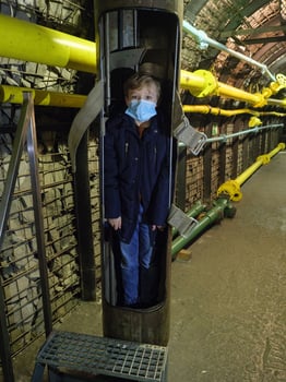 A child wearing a mask stands in a tunnel photo