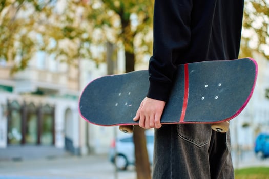Skateboarder holding worn pink skateboard at street photo