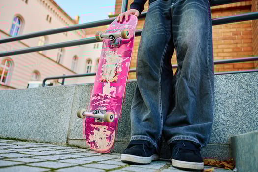 Skateboarder holding worn pink skateboard at street photo