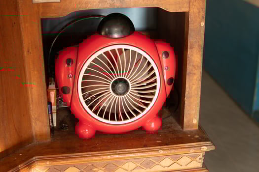 A small red children's model sitting fan is placed in a cupboard photo