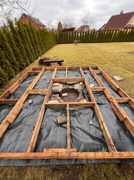 Wooden deck construction with protective sheet and framework in a landscaped backyard. photo