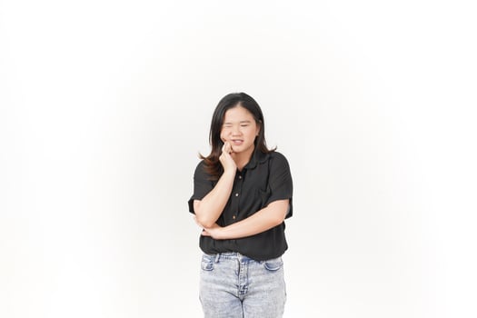 beautiful Asian woman poses with a pained expression, holding her cheek in discomfort due to a toothache against a white background photo