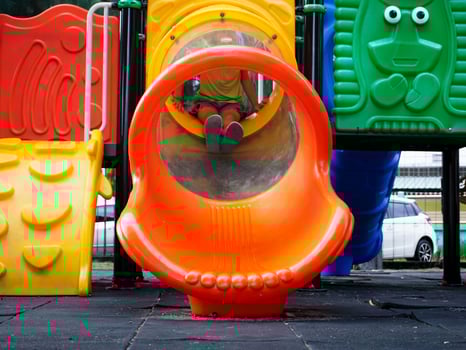 Children playing in the playground during summer vacation. Cute girl having fun on a colorful slide in an outdoor park. photo
