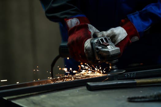 Craftsman using an angle grinder, creating bright sparks while working on a metal frame in the workshop. photo