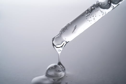 Pipette with facial serum pouring out of it on grey background. photo