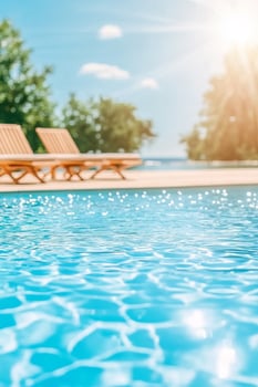 A tropical paradise resort pool with sparkling water under the sun and lounge chairs on a stylish deck photo