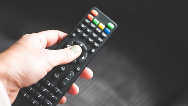 A hand holding remote control fingers black buttons tv photo