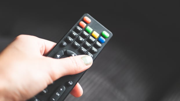A hand holding remote control fingers black buttons tv photo