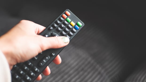 A hand holding remote control fingers black buttons tv photo