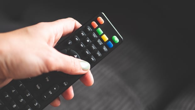 A hand holding remote control fingers black buttons tv photo