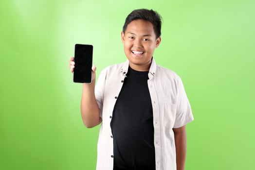 Young Indonesian Boy Holding Black Screen of Mobile Cell Phone photo