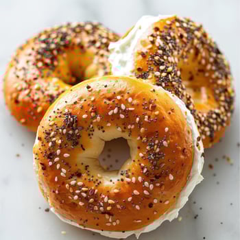 Close-up of two fresh baked bagels with a spread of cream cheese and sprinkles of poppy seeds. photo