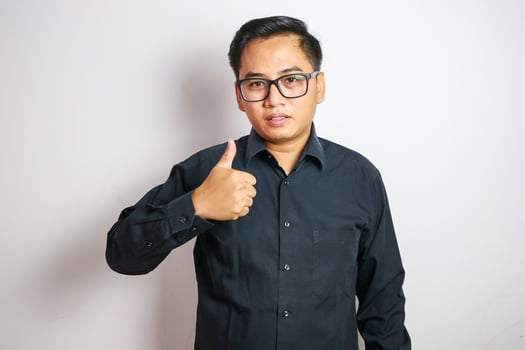 Young Asian businessman in suit showing thumbs up isolated on white background photo