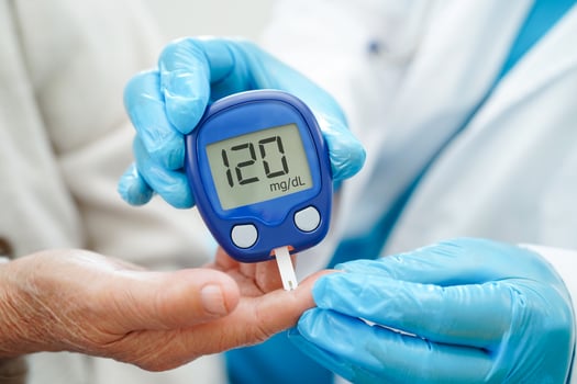 Asian doctor using digital glucose meter for check sample blood sugar level to treatment diabetes. photo