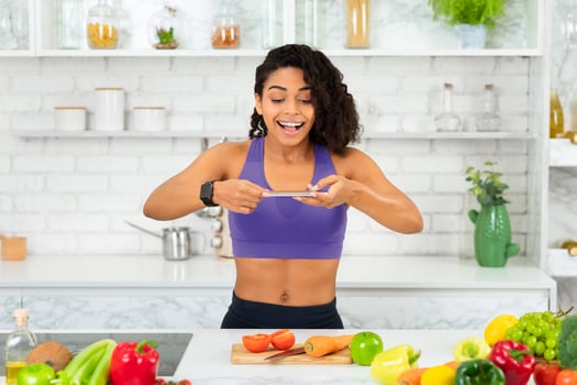 Food Blogger Concept. African girl recording step by step on smartphone at kitchen for her cooking vlog photo