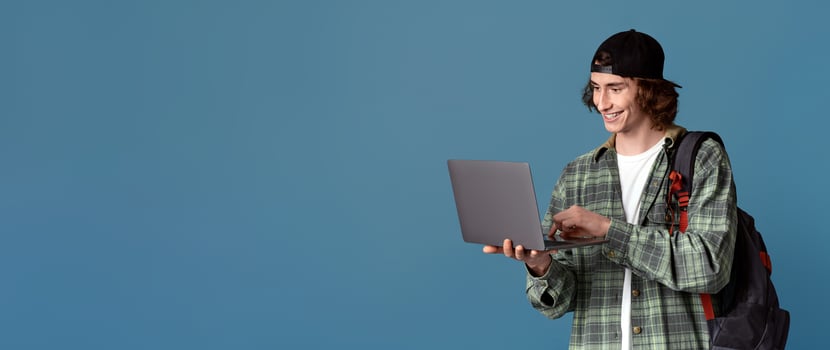 Online education concept. Teenage student with backpack using laptop for e-learning, turquoise background photo