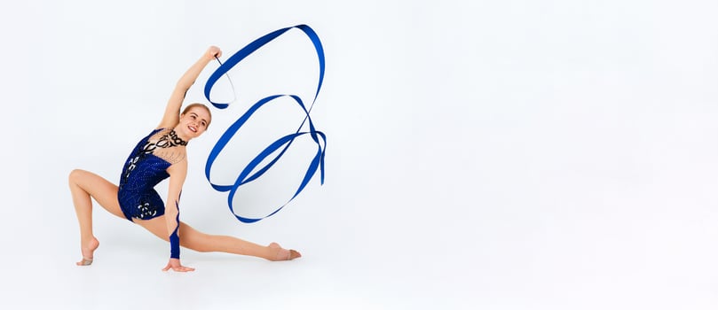 Sports contest. Skilled gymnast in beautiful red leotard performing with string on white background photo