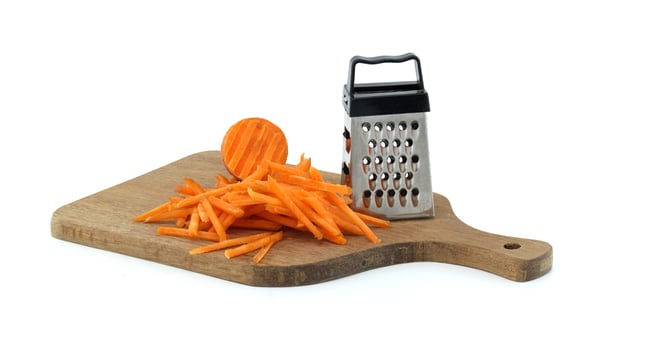 Wooden Cutting Board with Grated Carrot and Metal Grater photo