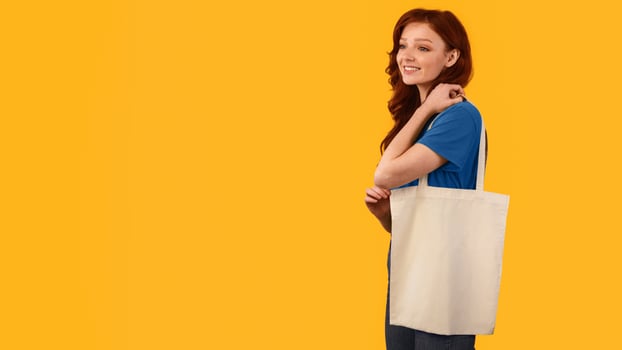 Girl With Flax Eco Shopper Bag Posing In Studio Over Yellow Background. No Plastic, Ecology Concept. Panorama With Empty Space photo