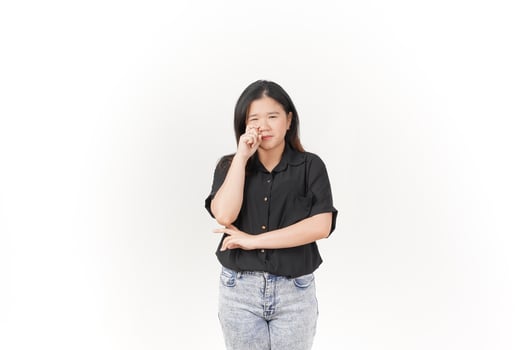 beautiful Asian woman poses with her fingers under her eyes, capturing a poignant crying expression against a white background photo