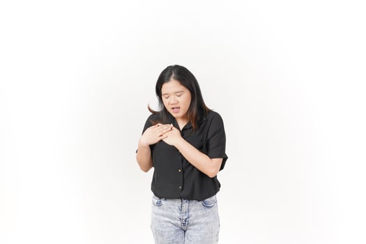 beautiful Asian woman holds her chest, displaying discomfort, against a clean white background photo