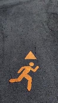 Safety sign indicating a running figure with a warning triangle. photo