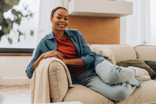 Beautiful, smiling African American woman wearing casual clothes, sitting on comfortable sofa photo
