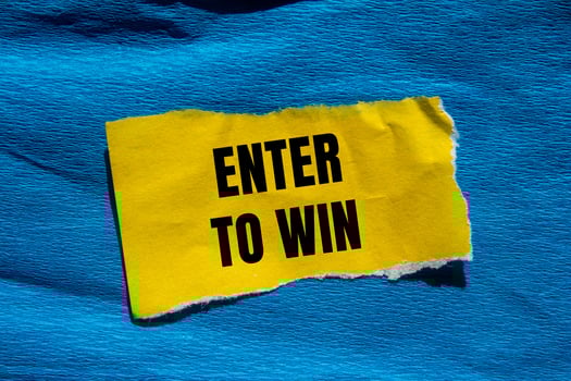 Enter to win message written on ripped torn yellow paper piece with blue background. Conceptual enter to win symbol. Copy space. photo