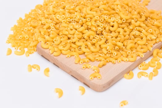 A Heap of Uncooked Chifferi Rigati Pasta on Wooden Kitchen Board. Fat and Unhealthy Food. Classic Dry Macaroni. Italian Culture and Cuisine. Raw Pasta photo
