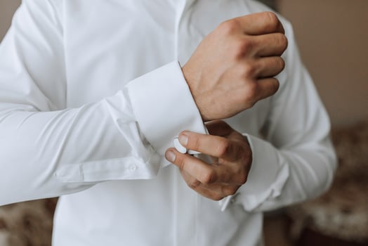 A man is getting dressed in a white shirt and is adjusting the cuff of the shirt photo