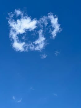 Fluffy white cloud shaped like a heart in blue sky photo