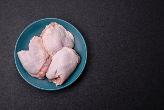 Raw chicken thighs with salt, spices and herbs photo