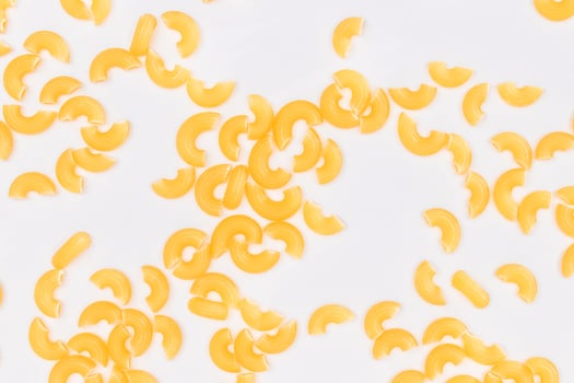 Scattered Uncooked Chifferi Rigati Pasta on White Background. Fat and Unhealthy Food. Classic Dry Macaroni Texture. Italian Culture and Cuisine. Raw Pasta photo