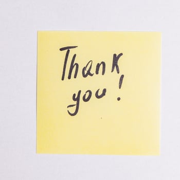 Word thank you on pink leaf on brown wooden table close up photo