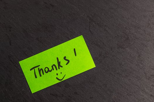 A small green note with the word thank you on a slate stone photo