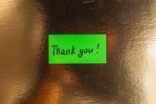 A small green note with the word thank you on a gold background photo