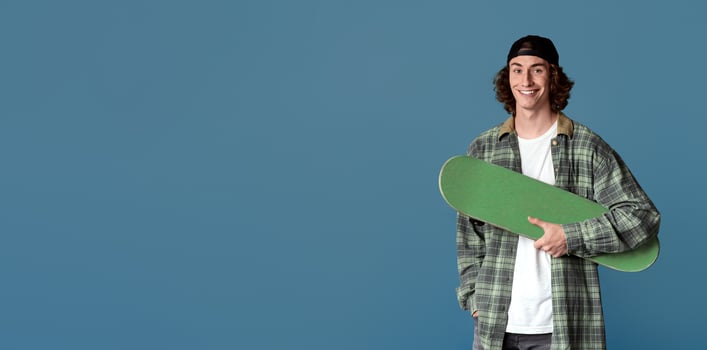 Sports and leisure concept. Happy teenager with skateboard on turquoise background photo
