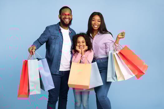 Black Friday Sales. Portrait of African American three cheerful people holding shopping bags with new clothes and gifts, family rejoice purchase, posing looking at camera, blue turquoise studio wall photo